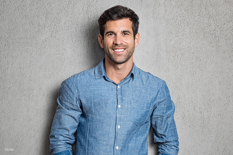 Man in a blue shirt leaning on a wall