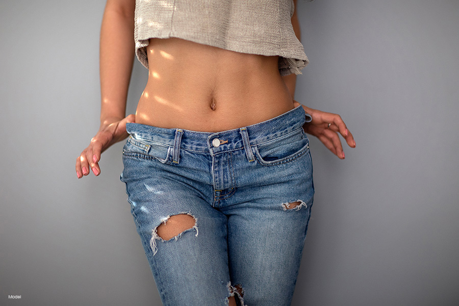 Fit woman in jeans showing her belly